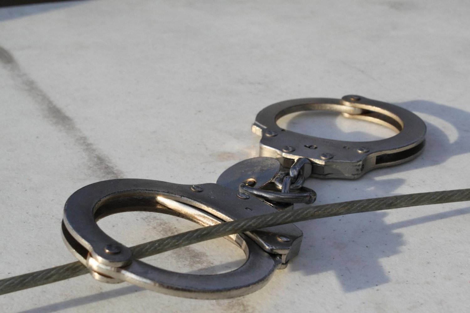 Metal handcuffs lying on a concrete surface, symbolising an arrest in Dubai